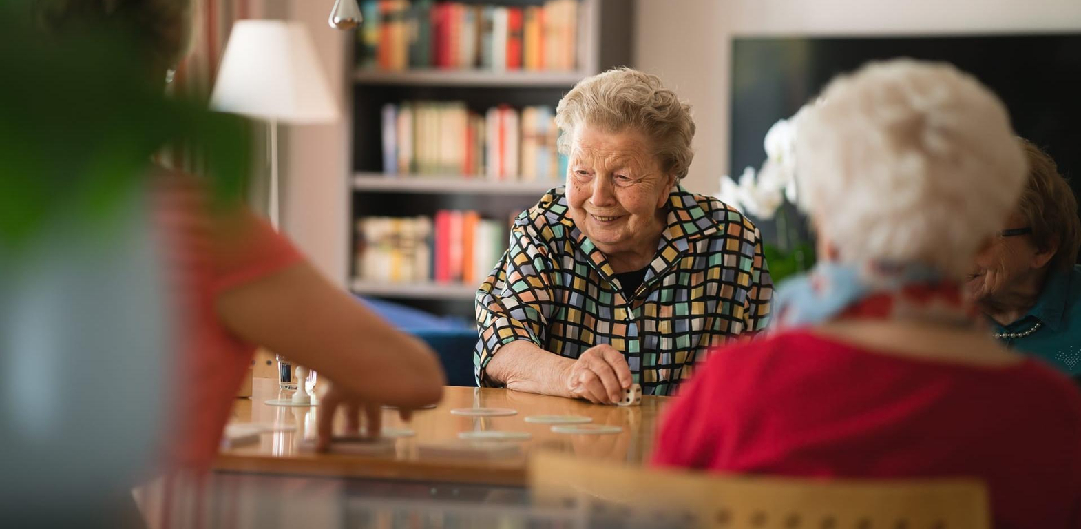Bewohnerin hat sich über Kostenübernahme Pflegeheim informiert und spielt nun Gesellschaftsspiele im Landhaus Pflege & Wohnen