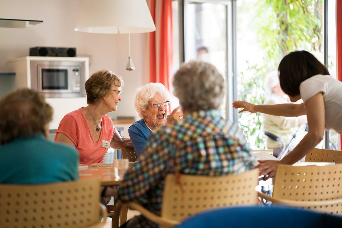 Bewohner spielen Gesellschaftsspiel mit Pflegern, lachen, Betreuung Altenheim in Hannover Landhaus Pflege und Wohnen