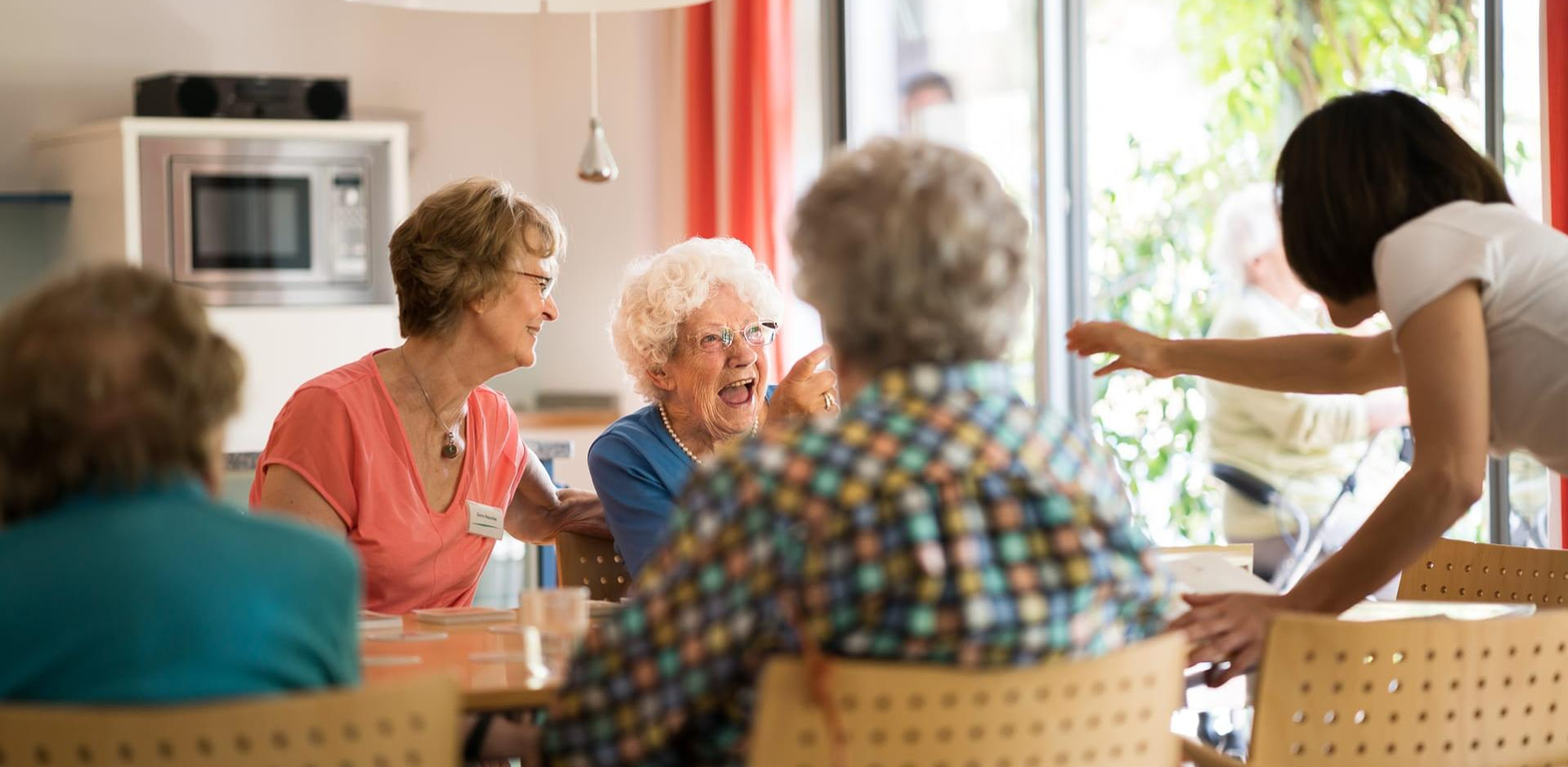 Bewohner spielen Gesellschaftsspiel mit Pflegern, lachen, Betreuung Altenheim in Hannover Landhaus Pflege und Wohnen
