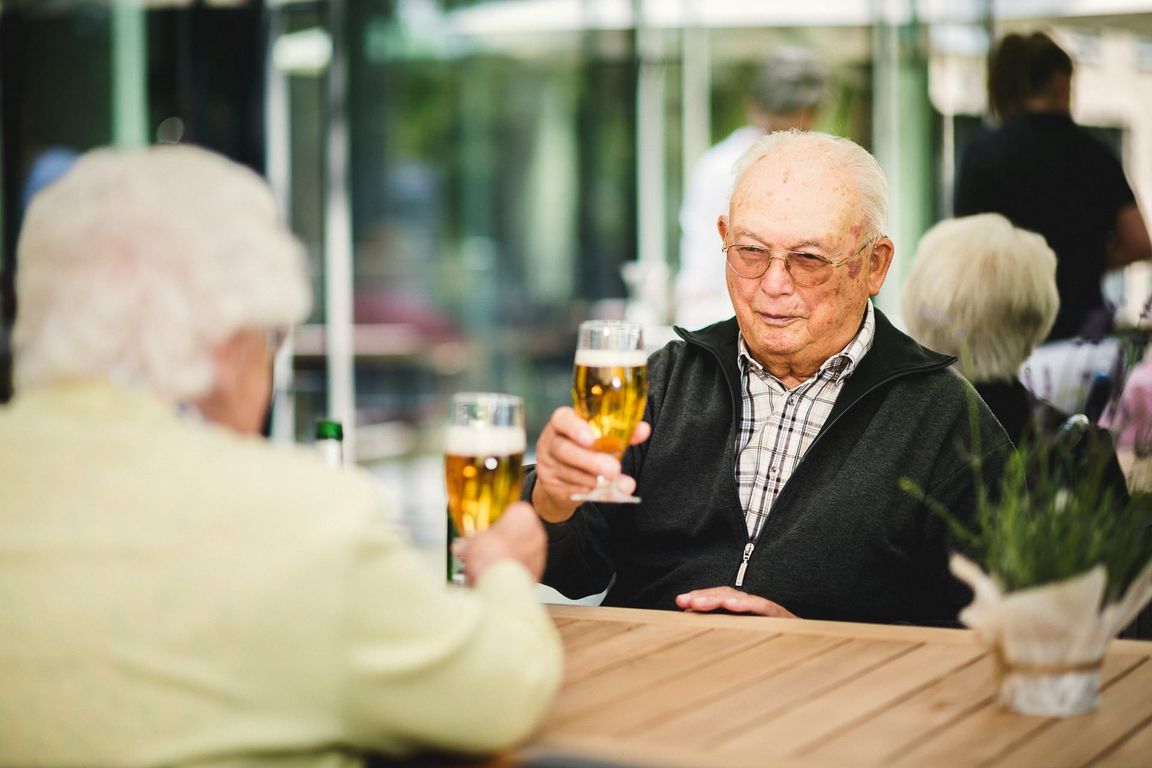 Ehepaar stösst mit Bier an auf Terrasse im Pflegeheim in Hannover Landhaus Pflege und Wohnen