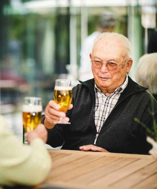 Ehepaar stösst mit Bier an auf Terrasse im Pflegeheim in Hannover Landhaus Pflege und Wohnen